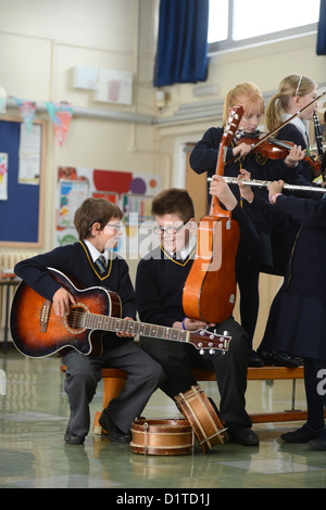 Jungen-Praxis auf ihre Gitarren während eine Musikstunde Muttergottes & St. Werburgh der katholischen Grundschule in Newcastle-under-Lyme, Stockfoto