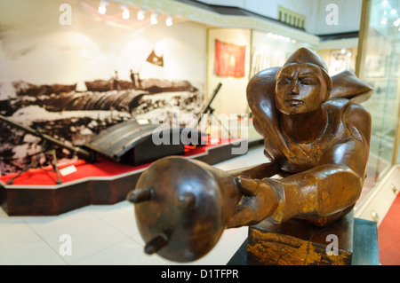 HANOI, Vietnam - eine stilisierte revolutionäre Statue auf der rechten und eine Ausstellung von Leichte Artillerie, Mörser im Hintergrund als Teil der militärischen Kampagnen der Revolution. Das Museum der Vietnamesischen Revolution in der Tong Dan Gegend von Hanoi, nicht weit vom Hoan Kiem See, wurde 1959 gegründet und ist mit der Geschichte der sozialistischen Revolutionären Bewegung in Vietnam gewidmet. Stockfoto
