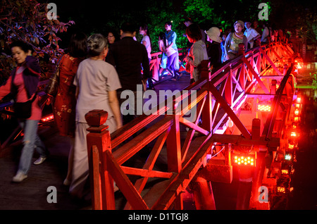 HANOI, Vietnam – Touristen besuchen die Huc-Brücke (Morgensonnenbrücke) bei Nacht. Die rot gestrichene Holzbrücke verbindet das Nordufer des Sees mit der Jade Island und dem Tempel des Jade Mountain (Ngoc Son Temple). Stockfoto