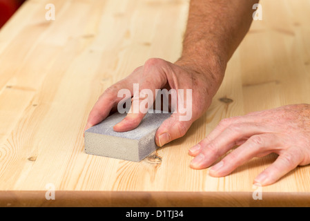 Mann mit Schleifblock auf Kiefer Boden oder Tisch Oberfläche Schleifen Stockfoto
