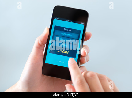 Frau hält und auf modernen mobilen Smartphone mit Login-Formular auf einem Bildschirm zu berühren. Stockfoto