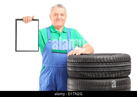 Ältere Arbeitnehmer auf Pkw-Reifen mit einem Klemmbrett isoliert auf weißem Hintergrund Stockfoto
