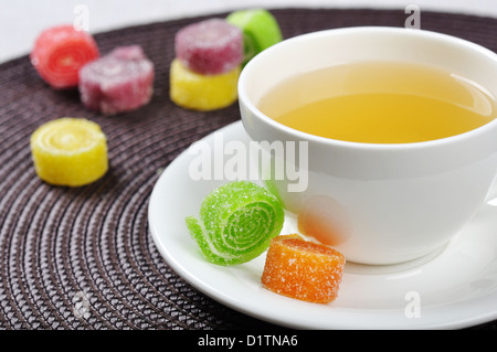 Tee in Tasse und süßes Gelee Bonbons auf Tisch Stockfoto