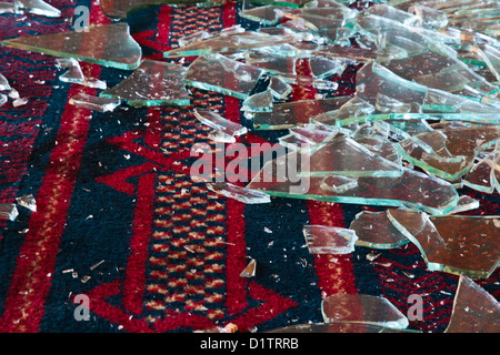 Glasscherben auf einem blau und rot gemusterten Teppich Stockfoto