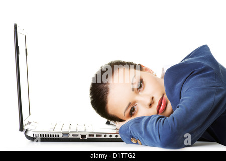 Schöne gelangweilt und müde Geschäftsfrau liegend auf Schreibtisch neben ihrem laptop Stockfoto