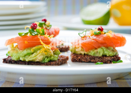 Dunkles Brot Sandwich mit geräuchertem Lachs, Avocado, garniert mit Schnittlauch und Pfeffer Stockfoto