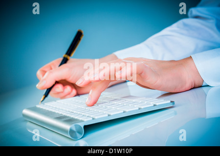 Weibliche Hände Tippen auf einer Tastatur auf blauem Hintergrund Stockfoto