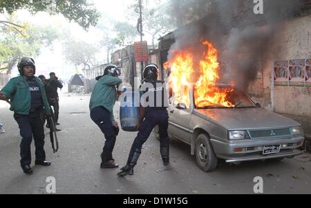 6. Januar 2013 - Dhaka, Bangladesch - JAN 06 2013-Dhak, Bangladesch-ein Bangladeshi Richtlinien trägt eine Wasser-Trommel zu versuchen, das Feuer auf dem brennenden Auto während die Daune, Abenddämmerung Streik im alten Teil von Dhaka auf Sunday.The Bangladesch National Party BNP zu entfernen und seine 18 Parteien-Allianz durchgesetzt werden landesweit bis Abenddämmerung Herunterfahren protestieren gegen die neuesten Anstieg der Heizölpreise Â © Monirul Alam (Credit Bild : © Monirul Alam/ZUMAPRESS.com) Stockfoto