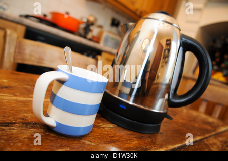 Blau und weiß entkleidet Cornish Geschirr Becher und einen Wasserkocher auf einem Holztisch in der Küche bereit, eine heiße Tasse Kaffee oder Tee zu machen Stockfoto