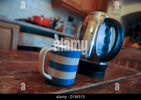 Blau und weiß entkleidet Cornish Geschirr Becher und einen Wasserkocher auf einem Holztisch in der Küche bereit, eine heiße Tasse Kaffee oder Tee zu machen Stockfoto