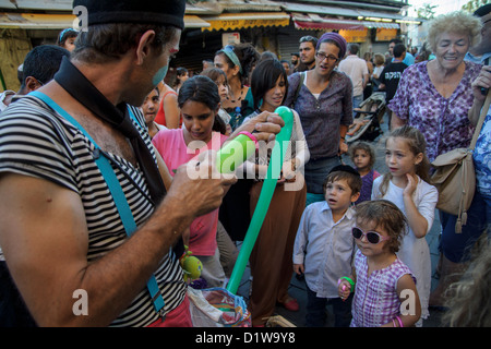 Jerusalem, Israel. Menschenmenge schaut ein Clown im Aug. 2012 "Balabasta" Straßenfest "Mahane Yehuda" Markt. Stockfoto