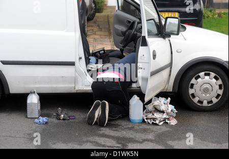 Junger Mann, die Durchführung von Wartungsarbeiten an seinem Opel van vor seinem Haus auf der Straße Stockfoto