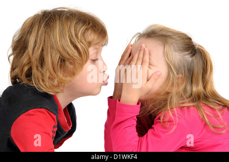 Kleiner Junge, eine Mädchen in weißen isoliert zu küssen versucht Stockfoto