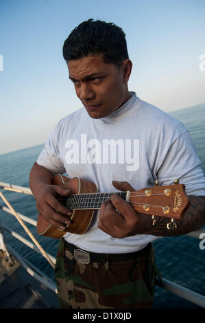 Luftfahrt-Maschinist Mate 3. Klasse Jerome Roberts von Rapid City, S.D., spielt eine Ukulele bei einem Stahl Strand-Picknick auf dem Vorschiff der Ticonderoga-Klasse geführte Flugkörper Kreuzer USS Mobile Bay (CG-53). Mobile Bay mit der John C. Stennis Strike Group in den USA bereitgestellt wird 5. Flotte Aufgabengebiet Durchführung von maritimer Sicherheitsoperationen, Theater Sicherheitsbemühungen Zusammenarbeit und Unterstützung Missionen für Operation Enduring Freedom(Jan. 7, 2013). (Foto: U.S. Navy Mass Communication Specialist 2. Klasse Armando Gonzales/freigegeben) Stockfoto