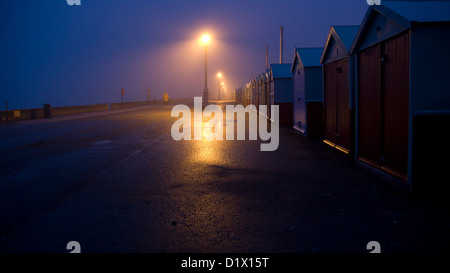 Strandhütten, Nacht, Straßenlaternen, Brighton und Hove, entfernte Figur, nasse Straße Stockfoto