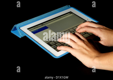 Ein weißes iPad mit Retina-Display in einem blauen Fall auf einem schwarzen Hintergrund mit einer jungen Frau eine Nachricht schreiben Stockfoto