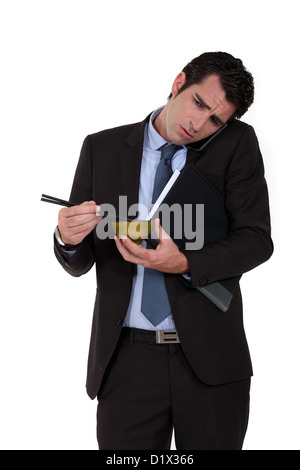 Geschäftsmann versucht, Nudeln essen während des Gesprächs am Telefon Stockfoto