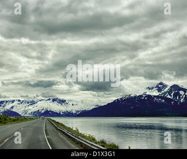 29. Juni 2012 - Halbinsel Kenai, Alaska, USA - Süd, malerische Seward Highway fahren Röcke die Basis der Chugach Mountains [Links] und bietet spektakuläre Ausblicke auf die vergletscherten, schneebedeckten Kenai Mountains eingerahmt von dramatischen Wolkenformationen. Sie steigen in der Ferne über Turnagain Arm--bei Ebbe das Wasser nur über die Bucht. Bezeichnet einen National Forest Scenic Byway, ein All-American Road und eine Alaska Scenic Byway, läuft Seward Highway 127 Meilen [204 km] von Anchorage, Seward, Kenai-Halbinsel, Chugach State Park und Chugach National Forest, ein Schaufenster der natürlichen beau Stockfoto