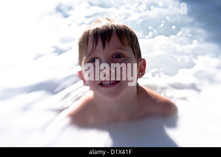 Kleiner Junge in einem Whirlpool, umgeben von Bubbles Stockfoto