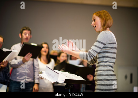 Eine junge Frau, die Durchführung einer kleinen Amateur Chorsänger singen Weihnachtslieder in Walisisch, Aberystwyth, Wales, UK Stockfoto