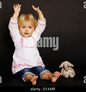 Zwei Jahre alten Säugling Blondine in weißen Hemd und Jeans auf schwarzem Hintergrund Stockfoto