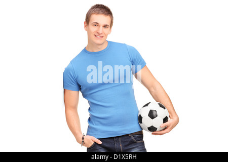 Ein junger Mann an eine Wand gelehnt und hält einen Fußball isoliert auf weißem Hintergrund Stockfoto