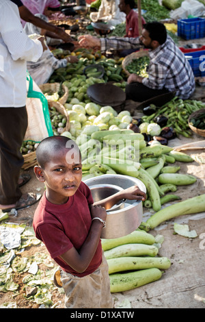 Armer Junge indische Straße tragen Töpfe vor einem Straßenmarkt. Andhra Pradesh, Indien Stockfoto