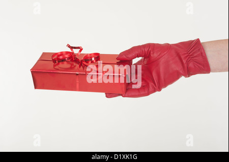 Geschenk in rotem Papier gewickelt und in eine Frau behandschuhten Hand gehalten Stockfoto