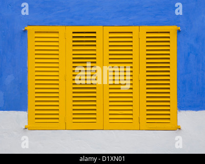 Portocolom, Mallorca, Balearen, Spanien. Gelben Fensterläden von blauen und weißen Haus in der Altstadt. Stockfoto