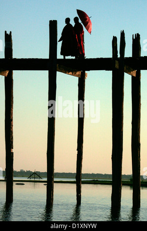 Buddhistische Mönche U Bein Brücke bei Sonnenuntergang, Amarapura, in der Nähe von Mandalay, Birma (Myanmar), Südost-Asien. Stockfoto