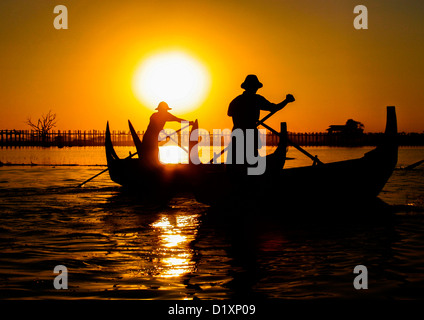 Burmesische Schiffer Rudern auf Taungthaman-See bei Sonnenuntergang, Amarapura in der Nähe von Mandalay in Burma (Myanmar), Südost-Asien. Stockfoto