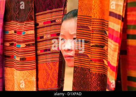 Eine Seite Mädchen spähte durch traditionelle gewebte Längen Tuch in das Dorf der Baw in der Nähe von Luang Prabang, Nordlaos, Asien Stockfoto