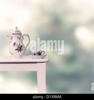 Vintage Teekanne und Tasse auf einem weißen Hocker Stockfoto