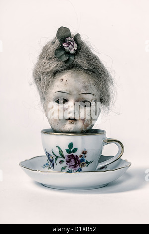 Kopf einer sehr alten, viktorianische Puppe in einer Teetasse Stockfoto