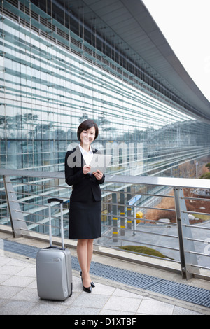 eine Geschäftsfrau mit einen Gepäck- und ein TabletPC Standing im Flughafen Incheon Stockfoto