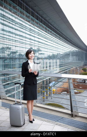 eine Geschäftsfrau mit einen Gepäck- und ein TabletPC Standing im Flughafen Incheon Stockfoto