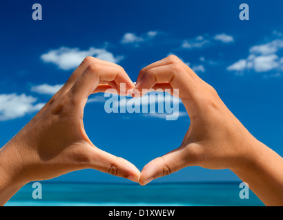 Weibliche Hand machen eine Herzform gegen einen wunderschönen blauen Himmel Stockfoto