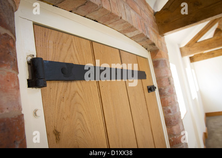 Schwarze Gusseisen Scharniere und Schrauben Sie an eine neue Tür in einem neu erbauten Gebäude. Stockfoto