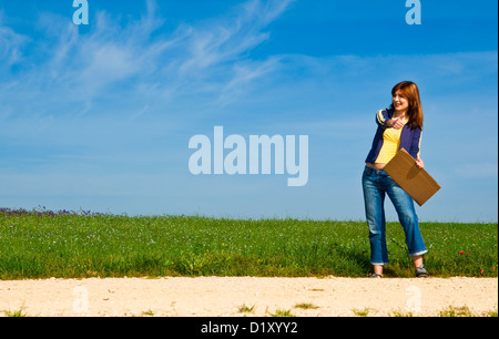 Junge Frau Trampen auf einer schönen grünen Wiese Stockfoto