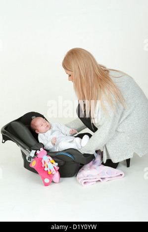 Junge Mutter, ihr 4 Wochen alten Babymädchen in einem Autositz Stockfoto