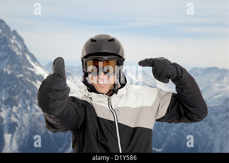 Skifahrer zeigt auf seinem Helm vor Bergen Stockfoto