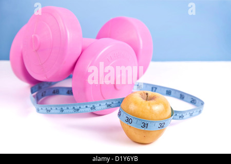 Große rosa Hanteln, grünem Apfel und Maßband, isoliert auf weiss. Stockfoto