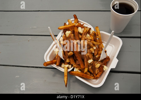 Kanadische Traditionsgericht der Poutine (Pommes frites, garniert mit Soße und Käse Quark) mit einer Tasse Kaffee serviert. Stockfoto