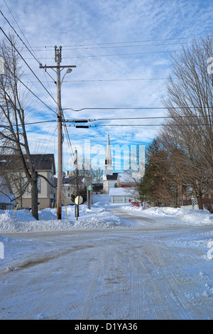 Ländliche Neuengland Ländliches Motiv mit Schnee bedeckt, Straßen, Telefon und elektrische Drähte, Bäume und eine entfernte Kirche. Stockfoto