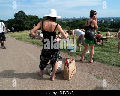 Menschen auf dem Parlamentshügel packen ihre Taschen nach einem heißen Tag im August Hampstead Heath in North London NW3 England Stockfoto