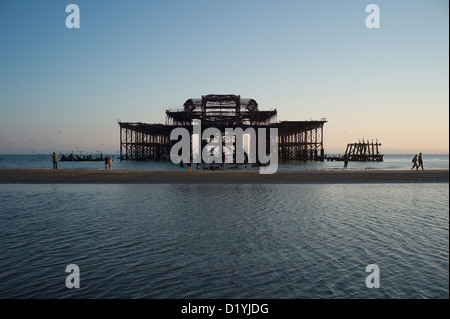 Menschen bei verlassenen West Pier, Brighton, außergewöhnliche Ebbe, Sonnenuntergang Stockfoto