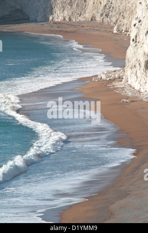 Der Strand und brechen Surfen unterhalb der Kreidefelsen kratzig unten, Durdle Door, Dorset, England, UK. Stockfoto