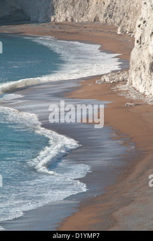 Der Strand und brechen Surfen unterhalb der Kreidefelsen kratzig unten, Durdle Door, Dorset, England, UK. Stockfoto