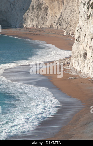 Der Strand und brechen Surfen unterhalb der Kreidefelsen kratzig unten, Durdle Door, Dorset, England, UK. Stockfoto