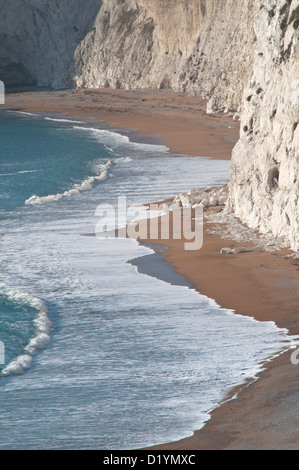 Der Strand und brechen Surfen unterhalb der Kreidefelsen kratzig unten, Durdle Door, Dorset, England, UK. Stockfoto